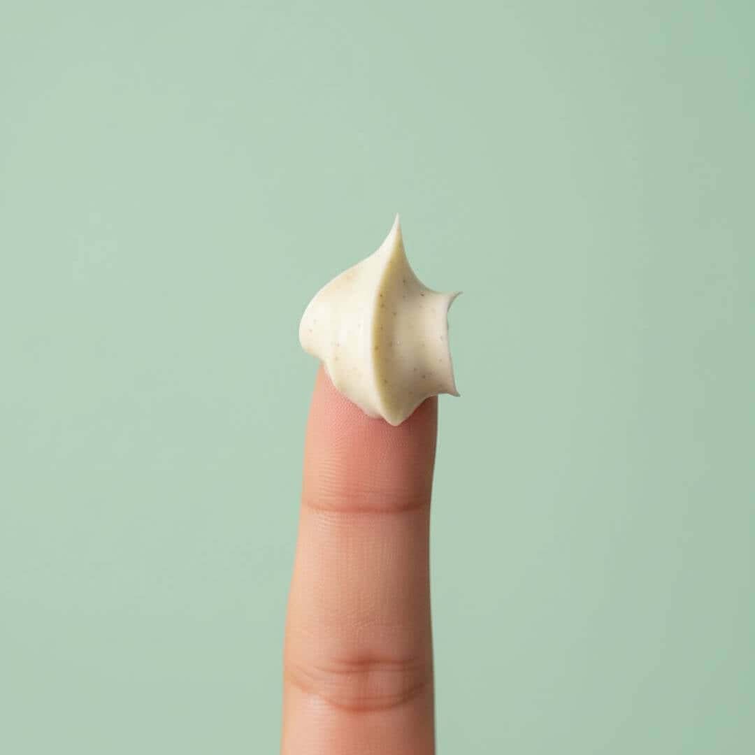 Une mèche de crème légère sur un doigt, illustrant le masque capillaire Le Soufflé pour pointes abîmées.