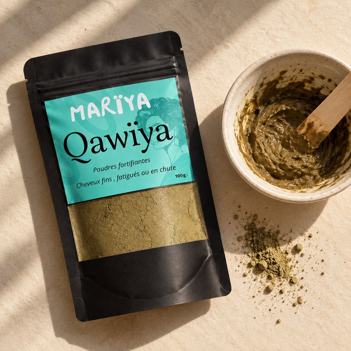 Sachet noir QAWÏYA et bol de pâte végétale dans une mise en scène aux tons naturels.