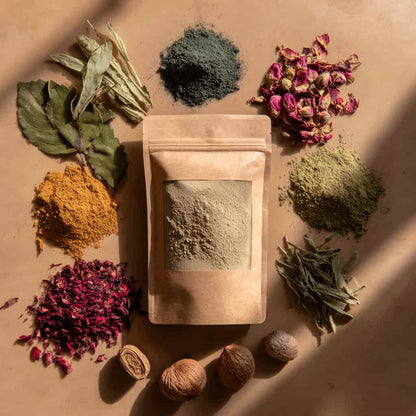 Pochette de poudre capillaire naturelle entourée d’ingrédients bruts – herbes, fleurs et épices – soins artisanaux marocains MARÏYA