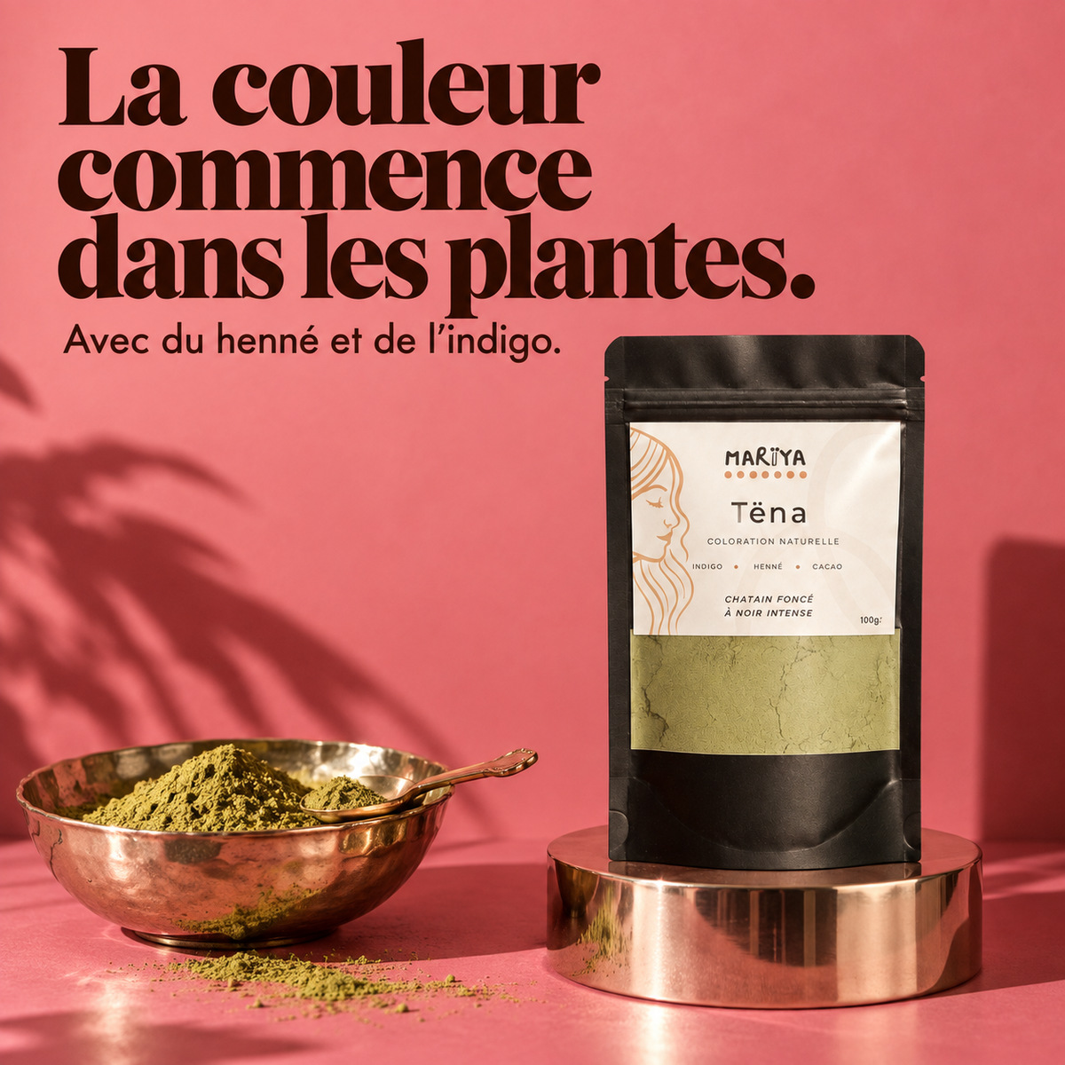 TËNA au henné et à l’indigo, avec une poudre végétale sur fond rose.