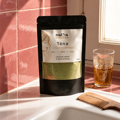 Sachet TËNA, peigne en bois et verre de thé dans un décor carrelé rose.